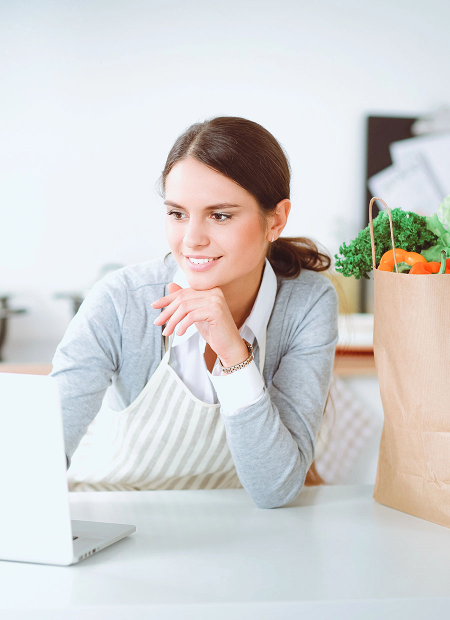Smiling woman online shopping using computer and credit card in kitchen